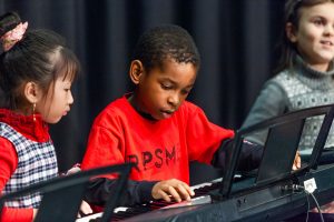 3 children playing on piano